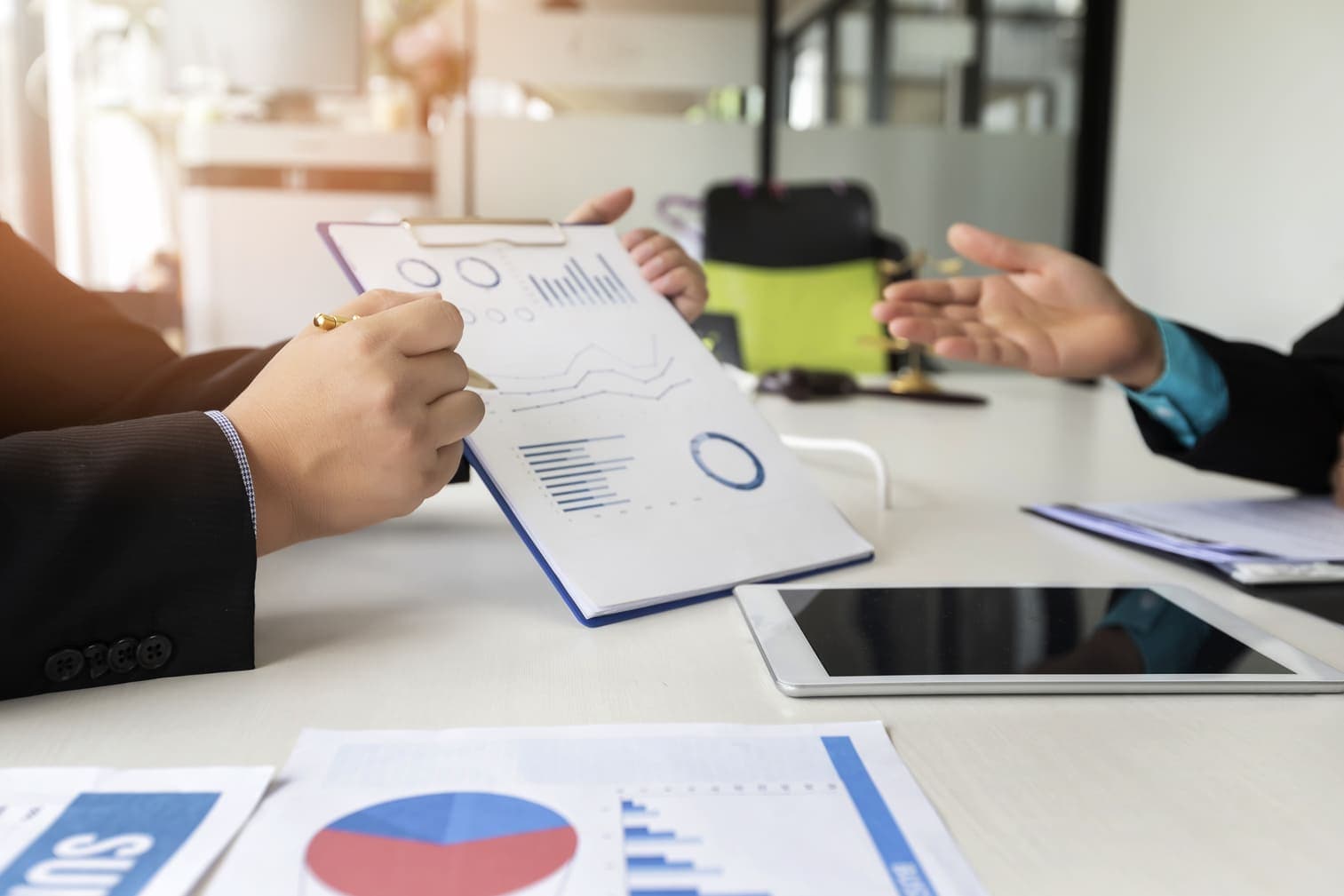 Advisers reviewing charts and a financial report at a meeting table